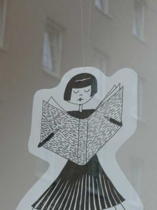 Die Zeichnung einer lesenden Frau hängt in der Buchhandlung im Fenster